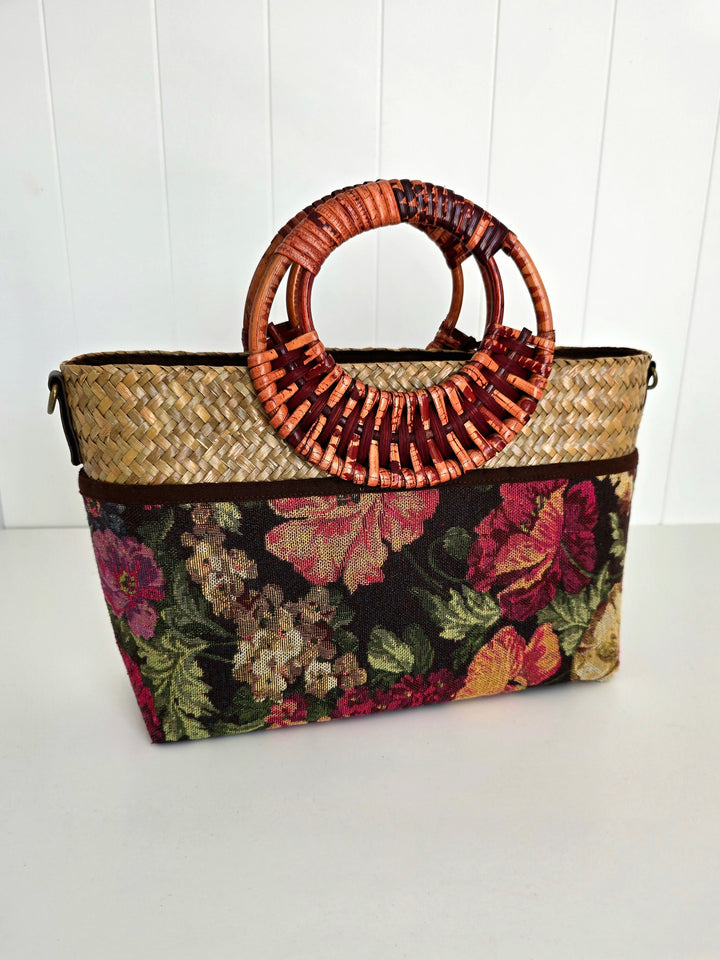 Floral-patterned handbag with woven handle on a white background