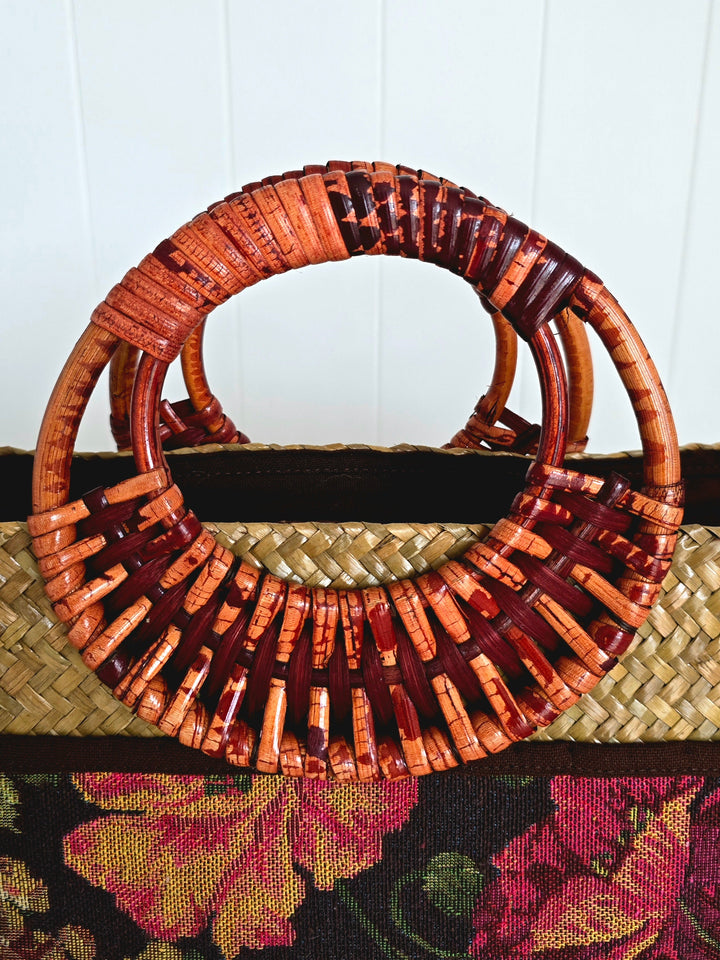 Woven handbag with decorative handle against a white background