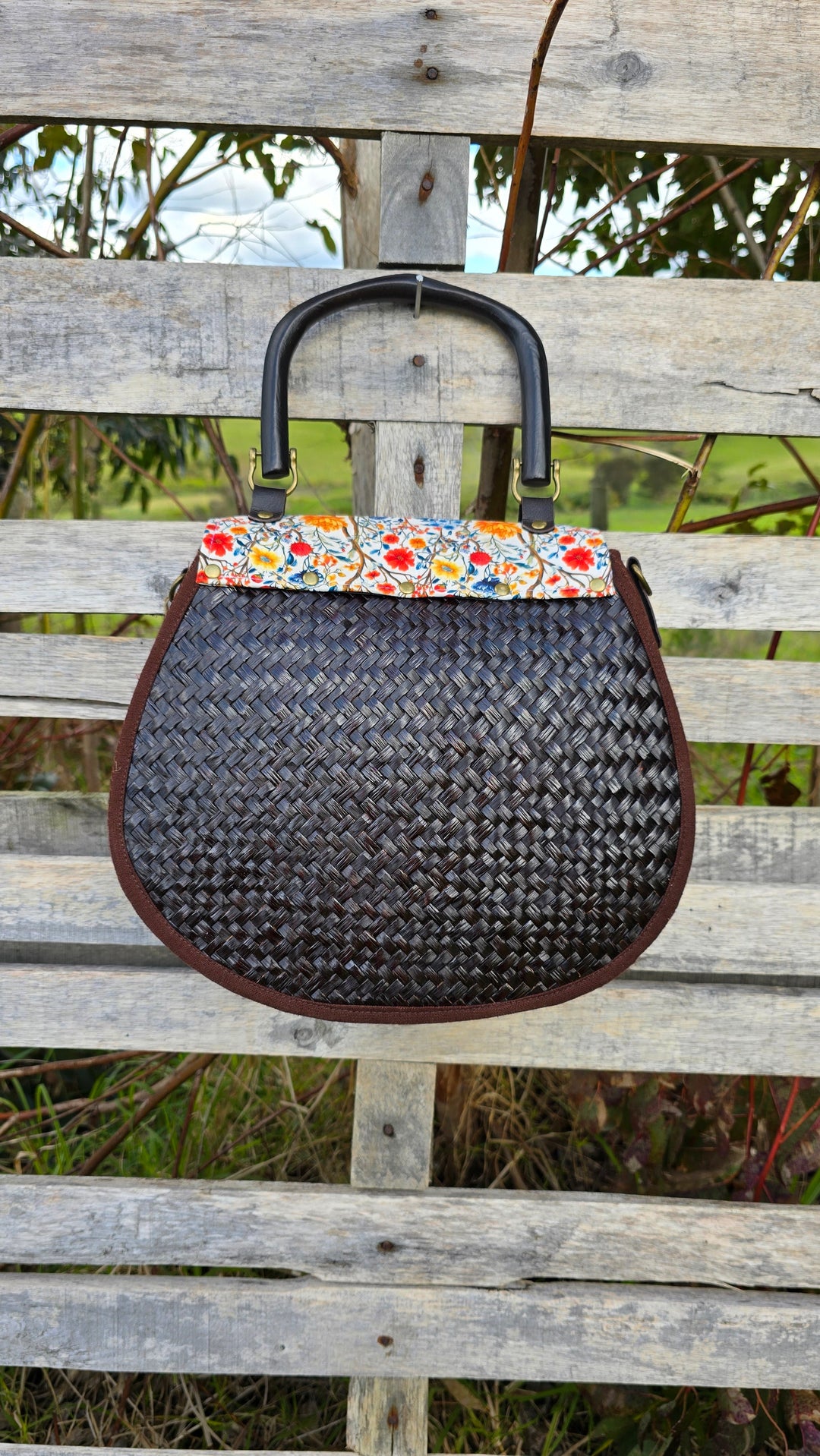 Woven handbag with floral patterned top on a wooden bench