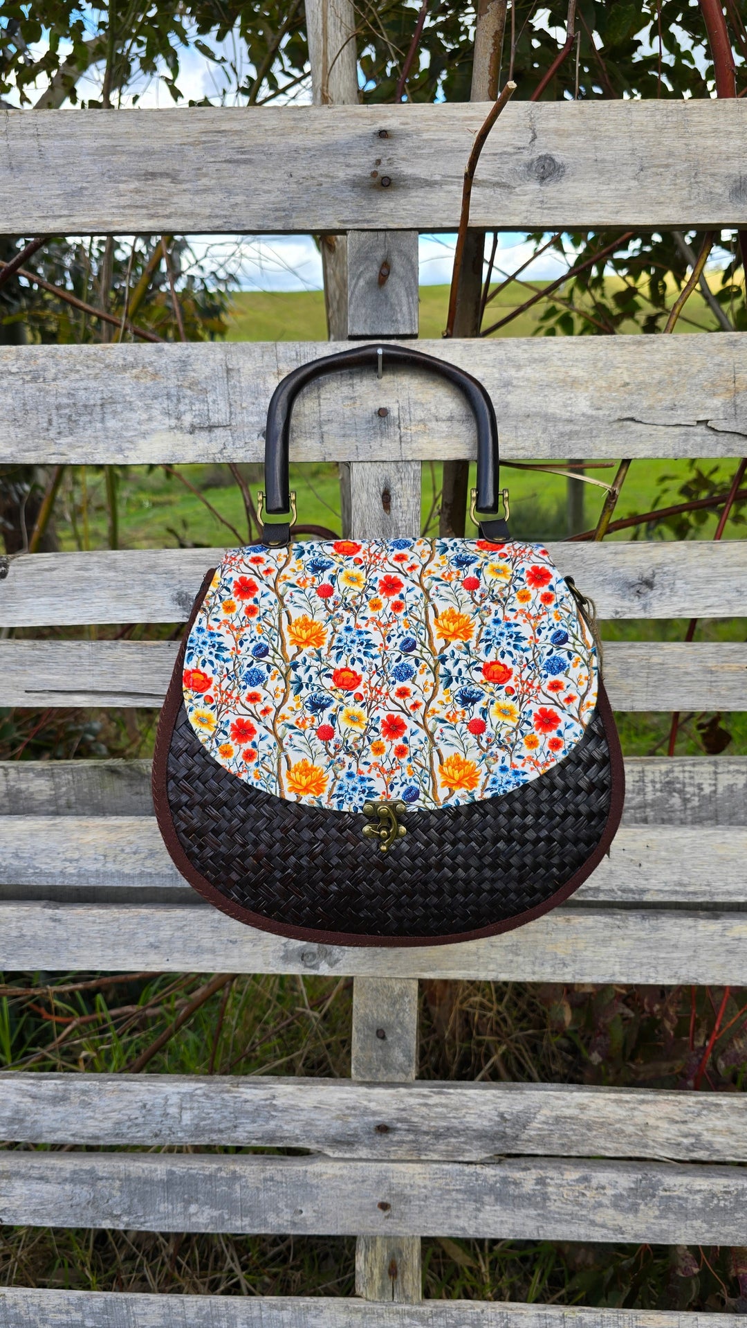 Floral-patterned handbag on a wooden bench with a natural background