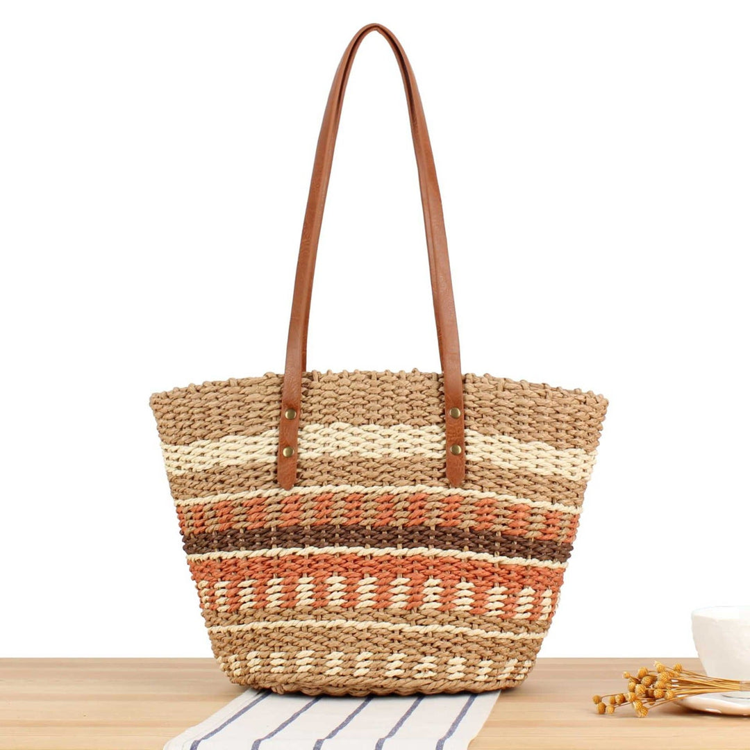 Woven straw tote bag with brown and beige stripes on a wooden surface.