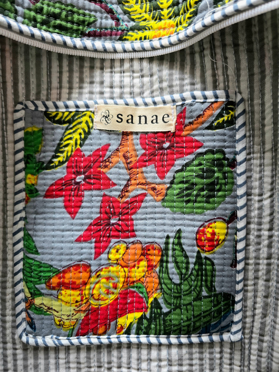 Floral patterned patch with 'sanae' brand label on a striped fabric background