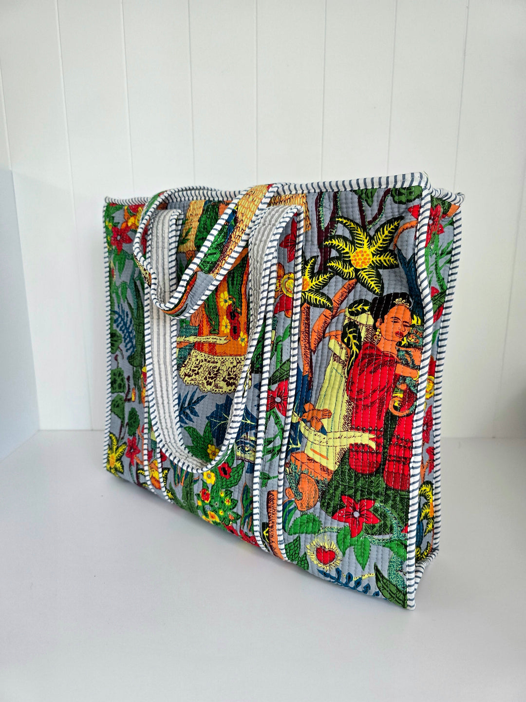 Colorful embroidered clutch bag with a floral and figure design on a white background