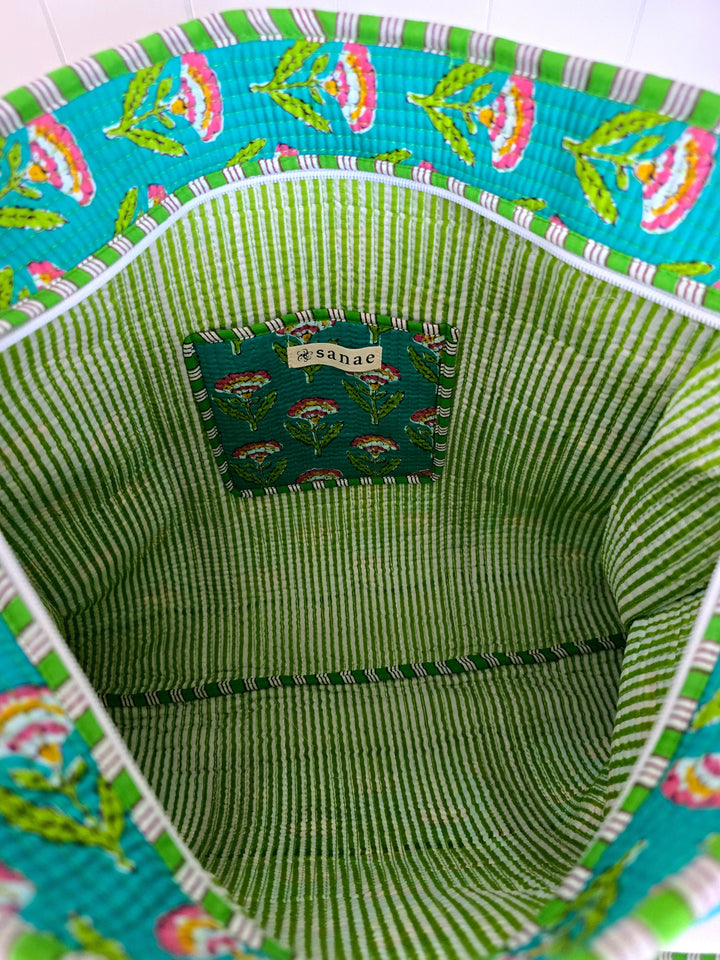 Close-up of a green woven basket with colorful floral pattern on top and bottom.