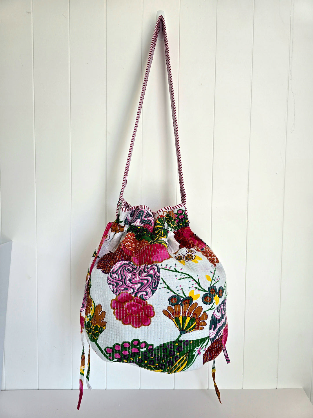 Colorful embroidered bag with floral patterns on a white wooden background