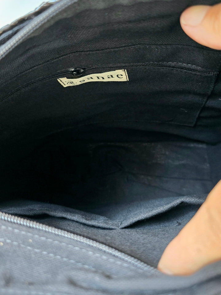 Close-up of a black bag with a visible brand label, held by a hand.