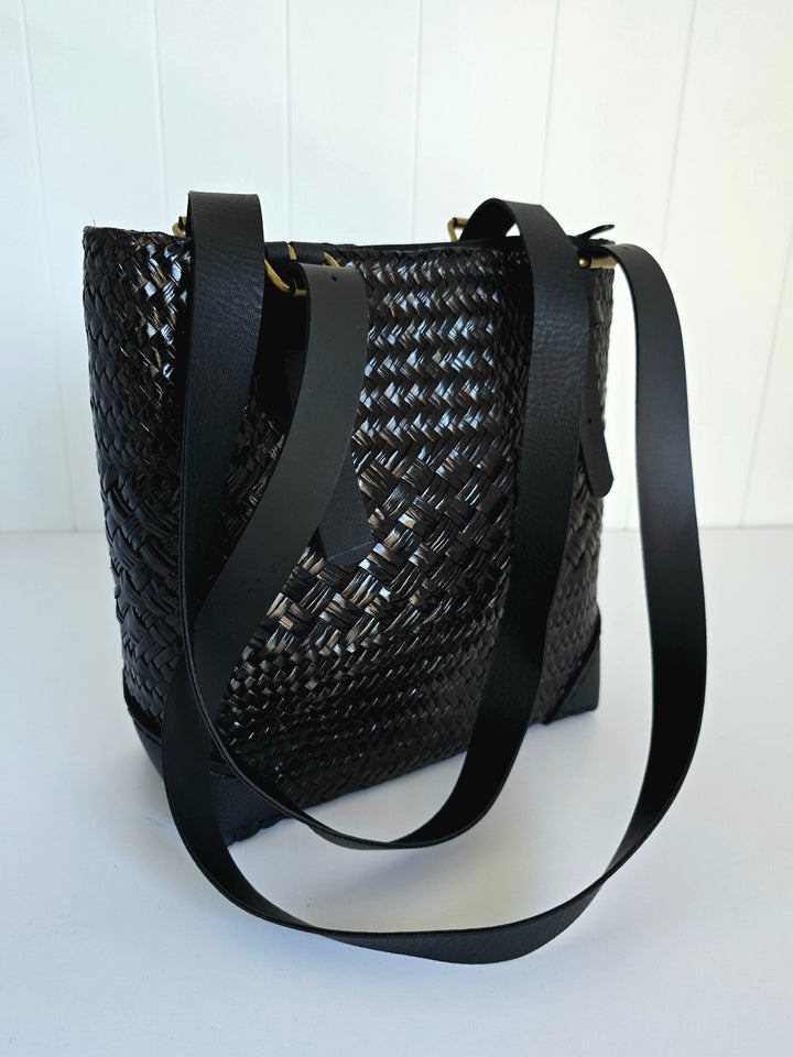 Black woven handbag with a strap on a white background